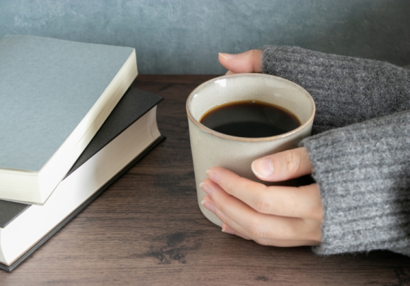 読書の合間にコーヒーでリラックスする女性